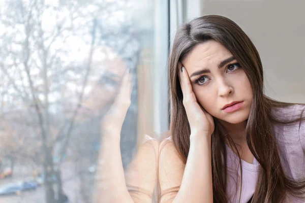 郁闷的年轻女子 在家里的窗户附近 — 图库照片