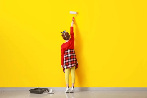 Little girl painting wall in room