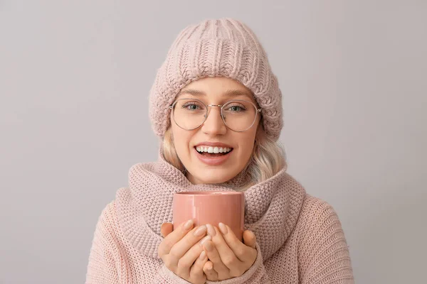 Beautiful young woman with cup of tea on grey background