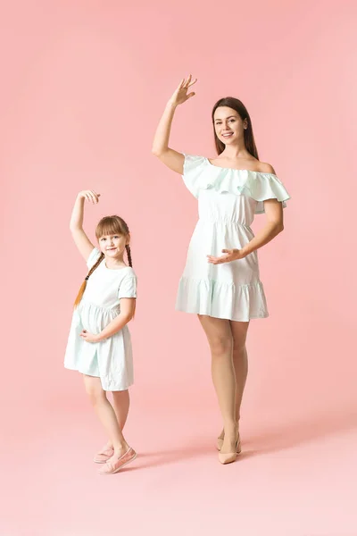 快乐的妈妈和她的小女儿在彩色背景下跳舞 — 图库照片