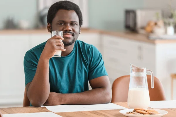 Young African-American man with milk in kitchen