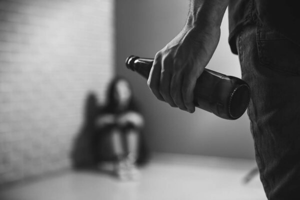 Drunk man standing in front of scared wife indoors. Concept of domestic violence