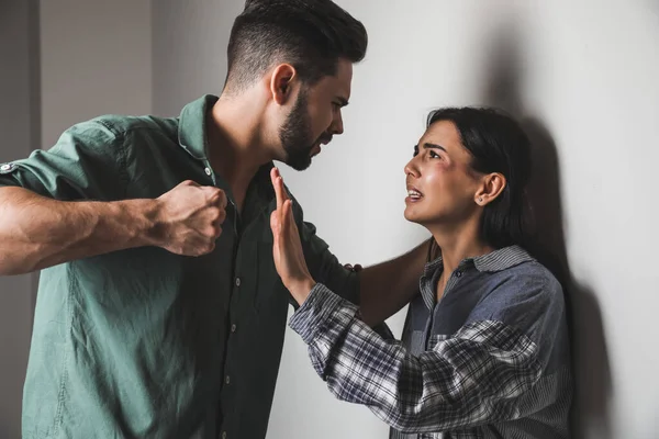 Angry husband trying to kill his wife indoors. Concept of domestic violence