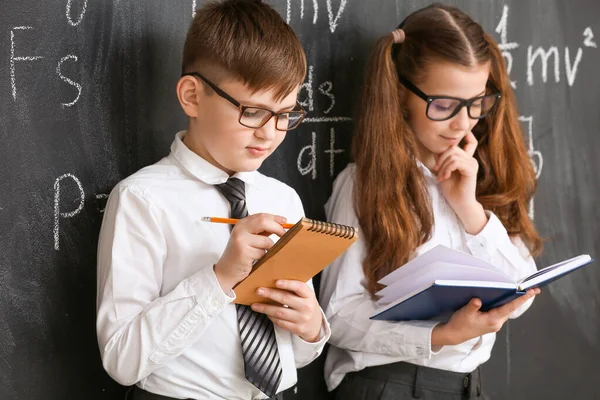 Cute little children near blackboard at physics lesson in classroom