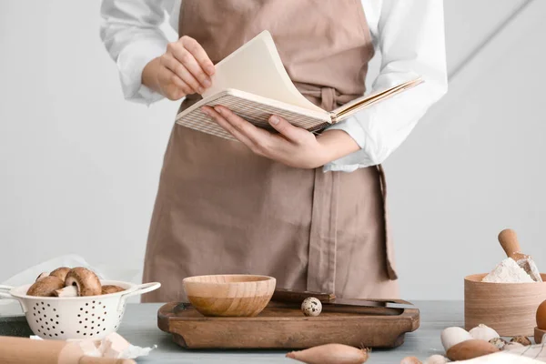 台所で料理を準備する料理本を持つ女性 — ストック写真