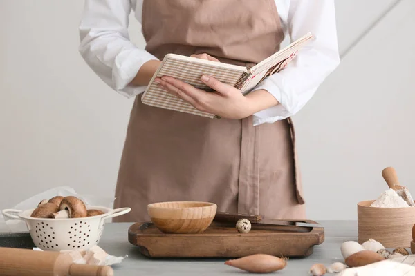 Woman with cook book preparing food in kitchen