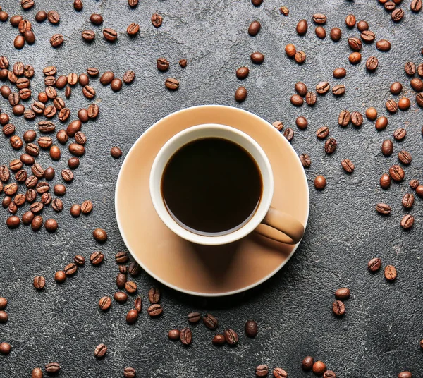 濃い色の背景に熱いコーヒーと豆のカップ — ストック写真