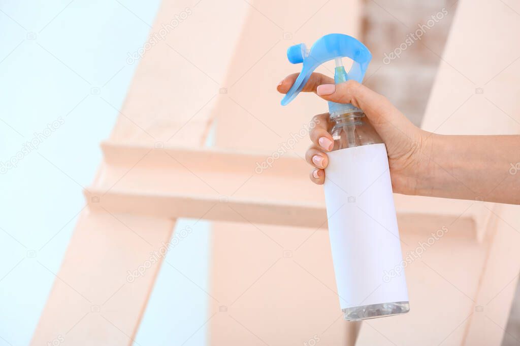 Woman spraying air freshener in room