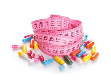 Beyaz arka planda mezurası olan kilo verme hapları