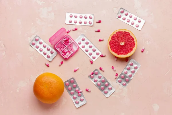Box with weight loss pills and grapefruit on color background