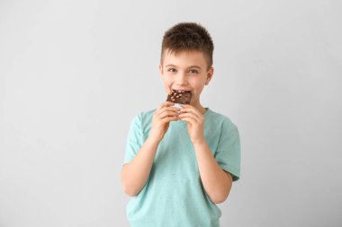 Küçük tatlı çocuk arka planda çikolata yiyor.