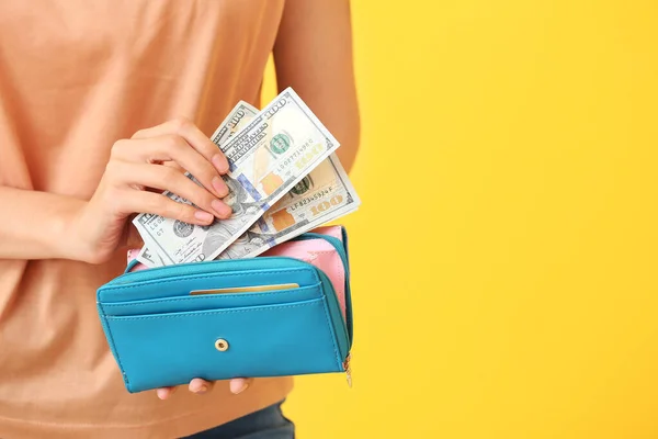 Young woman with wallet and money on color background, closeup