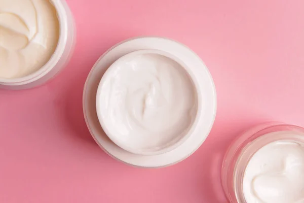 Jars of cosmetic cream on color background