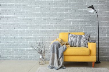 Koltuk ve lamba tuğla duvarın yanında.
