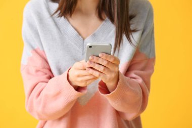 Renkli arka planda cep telefonu olan güzel genç kadın, yakın plan.