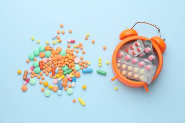 Renk arkaplanında farklı haplar bulunan alarmlı saat