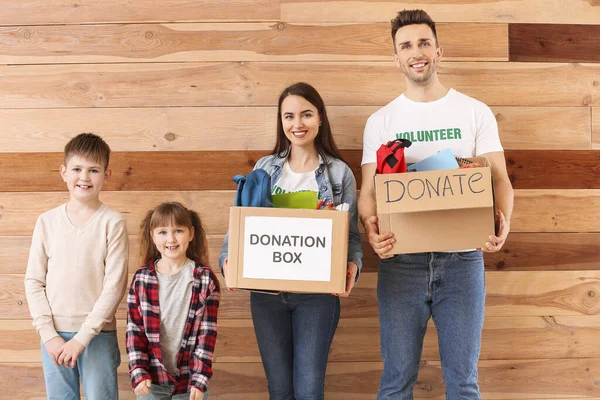 Volunteers with donations for orphans and little children on wooden background