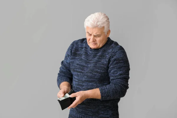 一个身披灰色背景钱包的可悲的老人 — 图库照片