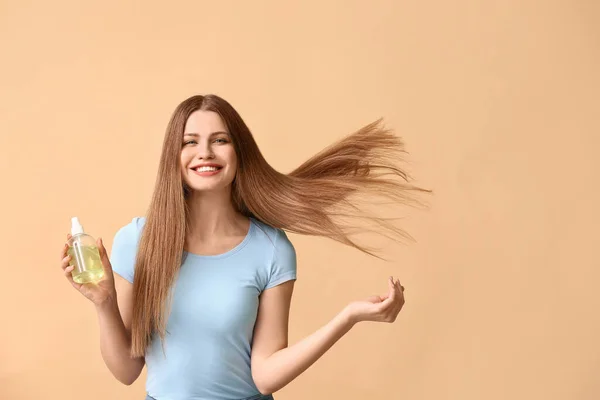 Beautiful young woman with hair spray on color background