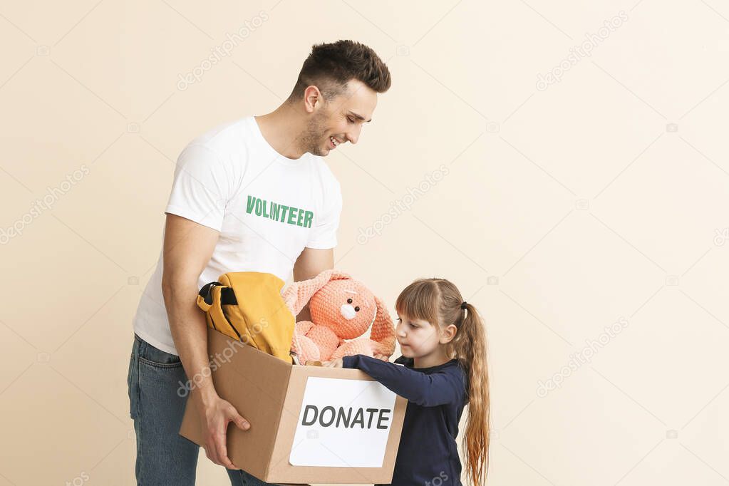 Volunteer with donations for orphans and little child on color background