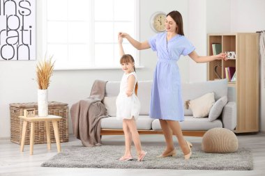 Mutlu anne ve küçük kızı evde dans ediyor.