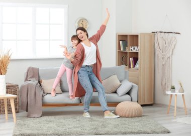 Mutlu anne ve küçük kızı evde dans ediyor.