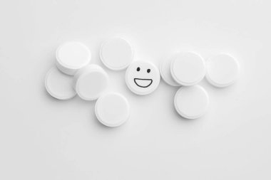 Beyazlar arasında mutlu yüzü çizilmiş bir hap, üst görüş.