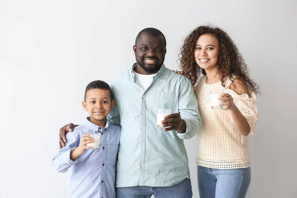 African-American family with milk on light background