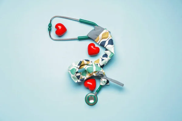 Stethoscope with cover and hearts on color background
