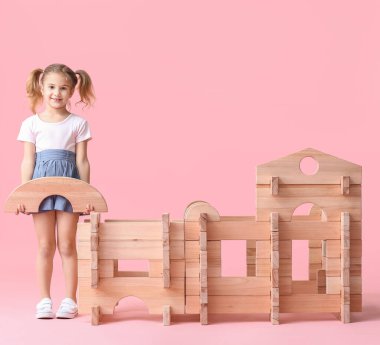 Küçük kız, arka planda paravan evle oynuyor.