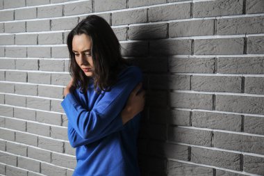 Depresyondaki genç kadın tuğla duvarın yanında