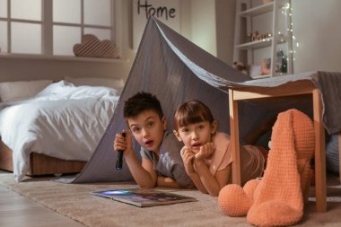 Korkmuş küçük çocuklar evde masal okuyor.