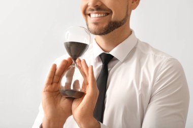 Hafif arka planda kum saati olan bir iş adamı. Zaman yönetimi kavramı