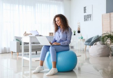 Evde çalışan bir kadın spor salonunda oturuyor.