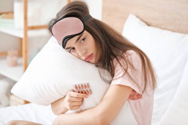 Yatak odasında uykusuzluk ilacı almış üzgün bir kadın.