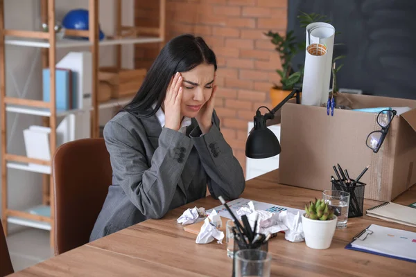 Sad fired woman at table in office