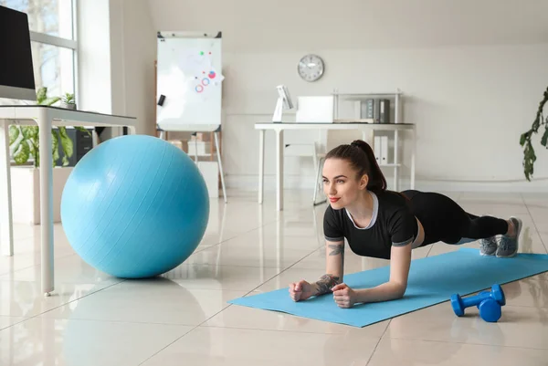 Young woman doing exercises in office