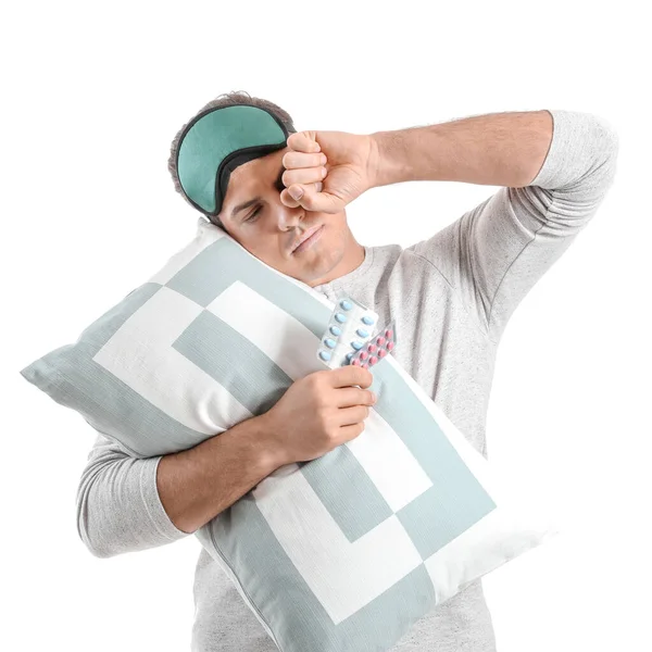 白い背景に睡眠薬と枕を持つ疲れた男 — ストック写真