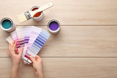 Renkli kumaşlar ve ahşap masa boyalı kadın elleri.