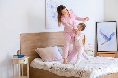 Mutlu bir anne ve kızının yatak odasında dans ettiği bir sabah.