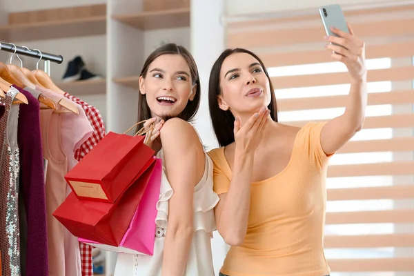 Genç kadınlar elbise mağazasında selfie çekiyorlar.