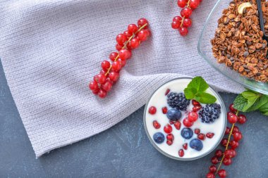 Lezzetli yoğurt, granola ve koyu arkaplanda böğürtlen.