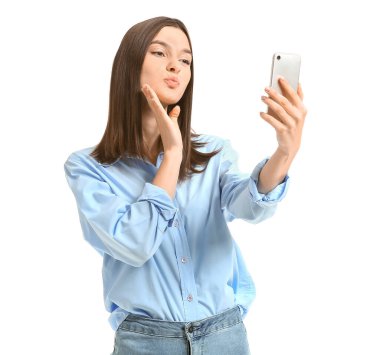 Güzel genç bir kadın beyaz arka planda selfie çekiyor.