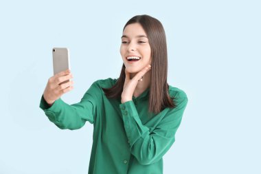 Güzel genç bir kadın, arka planda selfie çekiyor.