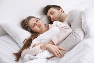 Genç çift yatakta uyuyor.