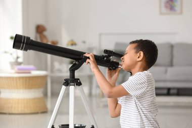 Evinde teleskopu olan küçük Afro-Amerikalı çocuk.