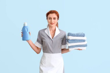 Temiz havluları ve arka planda yıkama sıvısı olan güzel bir oda hizmetçisi.