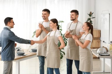 Teacher congratulating young people on successful completion of professional waiter courses clipart
