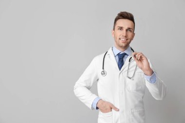 Gri arka planda el feneri olan erkek doktor.