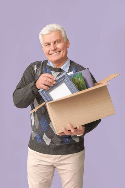 Happy fired mature man with personal stuff on color background